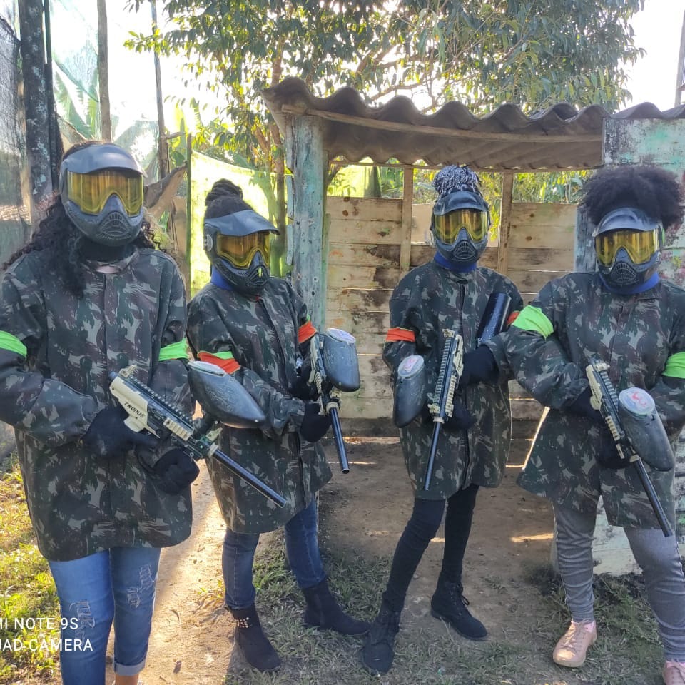 Grupo de jogadoras equipadas e reunidas para uma partida de paintball